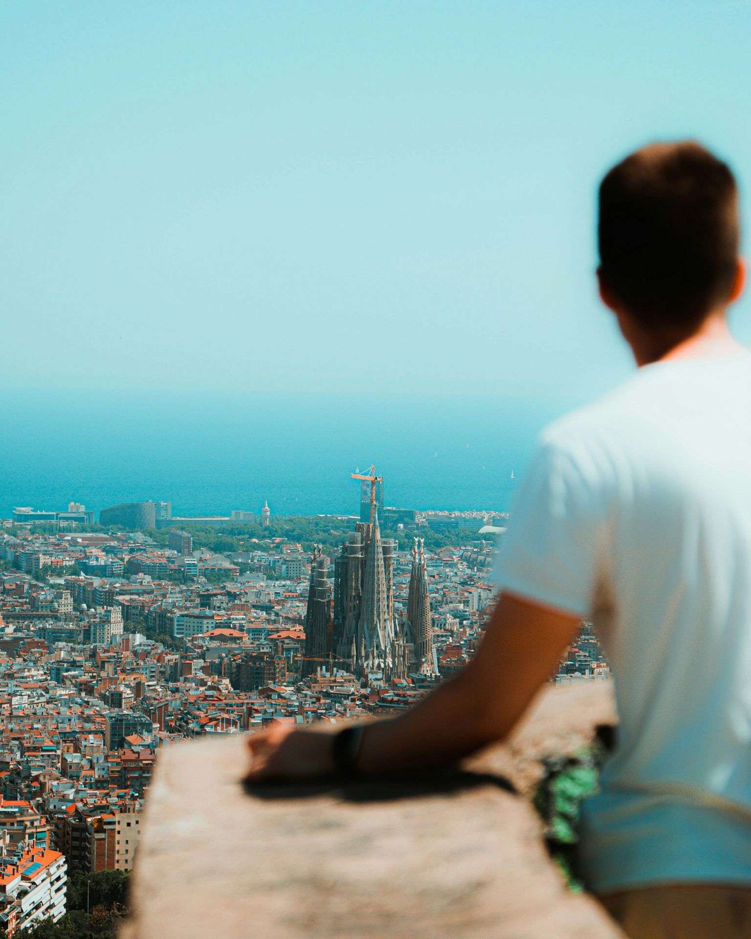 a man sitting on a ledge overlooking a city